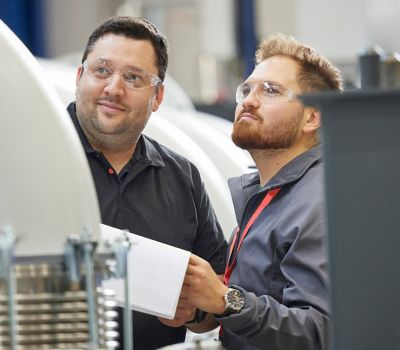 Two workers checking a vacuum pump